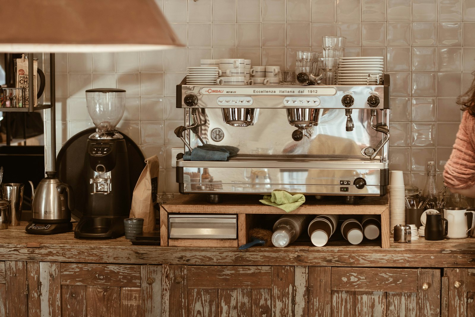 An independent café counter with a La Cimbali espresso machine on a worn wooden bar.